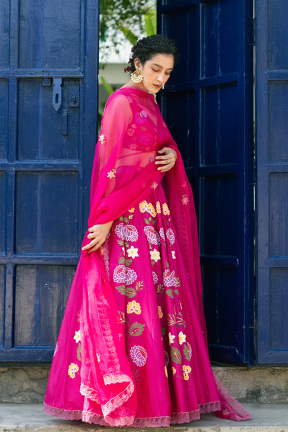 Woman in a bright pink traditional outfit with floral patterns standing in front of a blue door.

Baavli luxury designer store, New Delhi.
Indian wedding, lehenge, Bride, Indian bride, bridesmaid, Suit sets, Kaftan, sharara, jacket, kurta.
baavli launching its new collection, Dhan Mill, Hand painted, hand embroidered, Designer Label