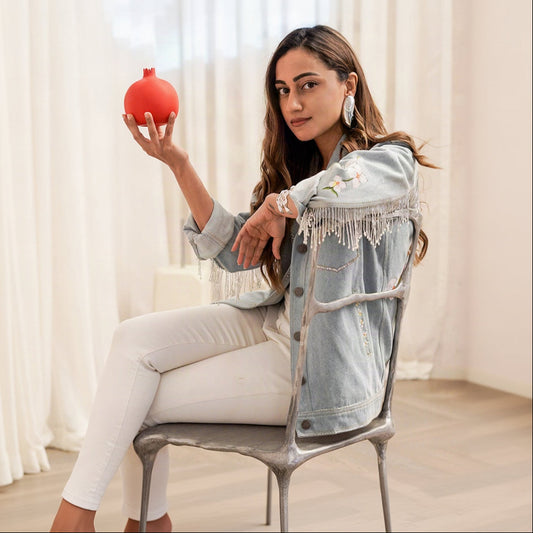 Woman sitting on a chair holding a red pomegranate in a softly lit room.
Fitoor Jacket.

Ridhi Khosla Jaan in baavli
Sourced by Design Aura 